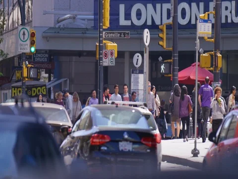 Medium shot of people walking down the street with cars moving in foreground dur Stock Footage 80347219