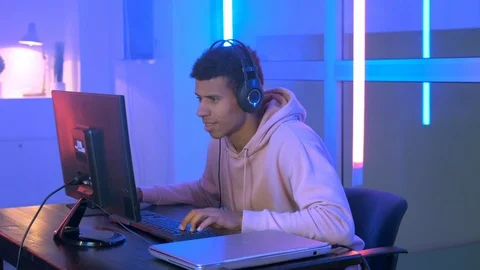 Medium shot of Persistent african gamer playing online shooter on pc in neon Stock-Footage 124406632
