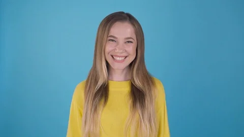 Medium shot plan portrait. Joyful girl in a bright yellow sweater on a blue Vídeos de archivo 109243047