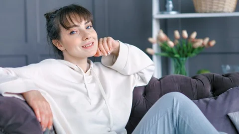 Medium shot portrait smiling young handsome female sitting leaning back on couch Stock Footage 93402302