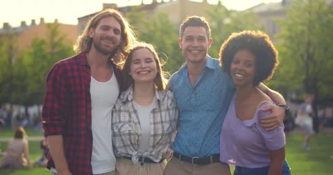 Medium shot of positive multiracial young friends having fun at park hugging and Video stock 157961199