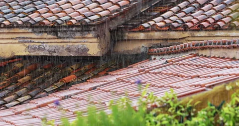 Medium shot of pouring rain on the tiles and gutters of a city roof Stock Footage 156965309