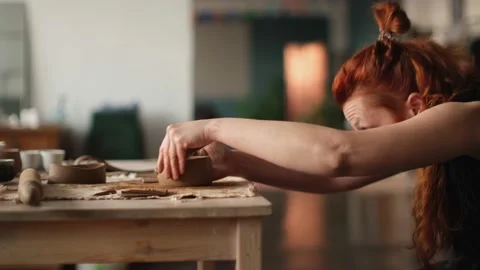 Medium shot of redhead ceramic artist cut clay for ceramic teapot Stock Footage 236373378