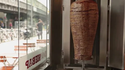 Medium shot of a rotating döner kebab meat cone at a Kreuzberg fast food stand Stock Footage 312662612