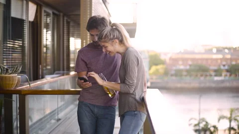 Medium shot side view of cheerful young couple looking at photos on smartphone Stock Footage 277969999