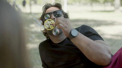Medium shot of single bearded father blowing soap bubbles Stock Footage 161148260