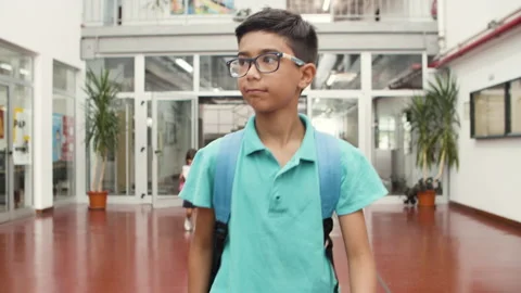 Medium shot of smiling boy in eyeglasses walking in school. Stock Footage 153830873