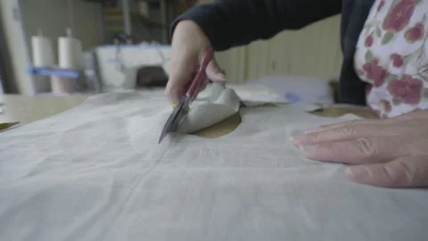 Medium shot of someone cutting fabric with large scissors on a work table Video stock 344321283