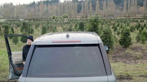 Medium shot of staff loading a tree on top of a car at a tree farm 動画素材 73068644