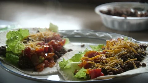 Medium Shot of Steamy Tacos with Cheese, Lettuce, Tomatoes, on flour Tortilla Stock Footage 199506610