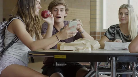 Medium shot of students examining cell phone in school cafeteria / Mapleton, Stock Footage 68218132