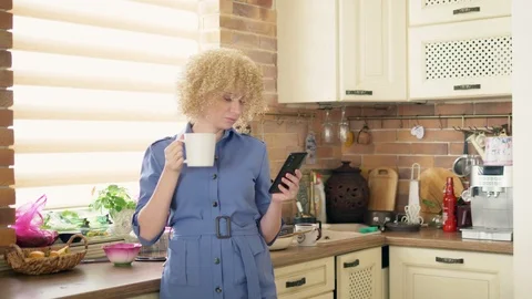 Medium shot. stylish woman using a mobile phone in the kitchen at home Vidéo 119449859