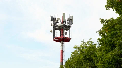Medium shot of a telecommunications 5G cell tower jutting up behind trees Stock Footage 202604590