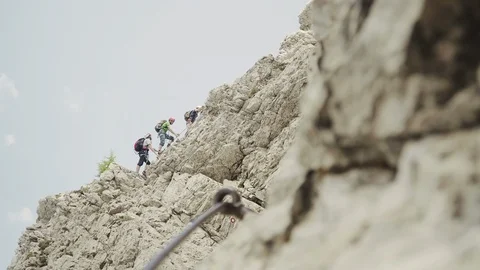 Medium shot of three climbers climbing on a rocky wall Stock Footage 98700451