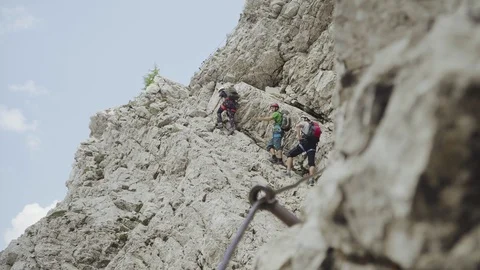Medium shot of three climbers in the wall looking and pointing other mountains Stock Footage 98698792