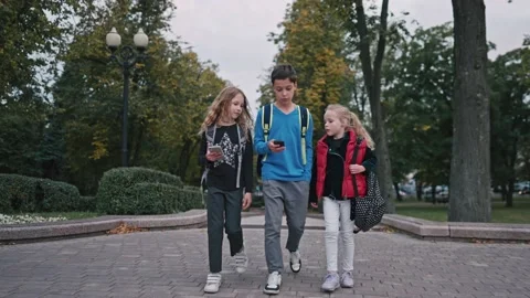 Medium shot of three pupils with backpacks going out of school and talking. Boy Stock Footage 161248316
