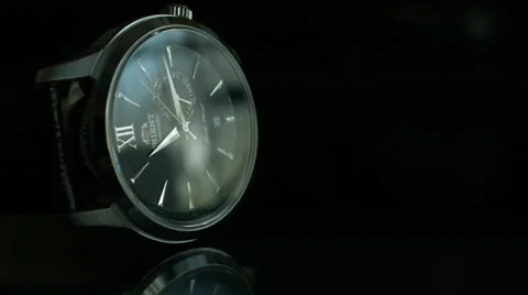 Medium shot of a tilted Black Wrist Watch on a dark reflective surface Stock Footage 68191997