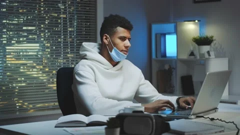 Medium shot of Tired multiethnic man with protective mask working home late at Stock Footage 131536993