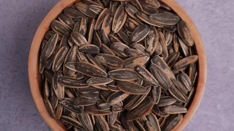Medium shot top view of the spinning wooden bowl of sunflower seeds Stock Footage 275489059