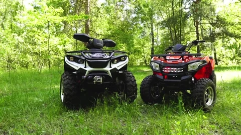 Medium shot. Two ATVs are in the forest. The camera is filming the ATV. Two ATVs Stock Footage 139884433
