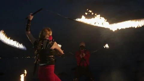 Medium shot of two fire artists performing their act at a fire show on a beach Stock Footage 144746376