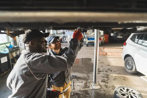 Medium shot of two mechanics doing a clutch replacement in a repair shop. Stock Photos
