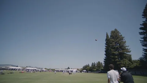 Medium shot of two men ejecting football from ball ejector on field Stock Footage 120303935
