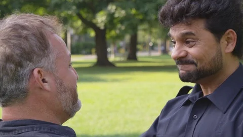 Medium Shot - Two men embrace each other when meeting at a park - shot on RED Stock Footage 124909720