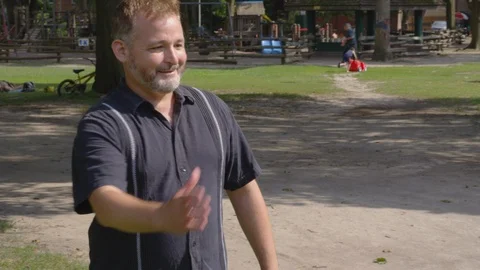 Medium shot - Two men shake hands in a park - shot on RED Stock Footage 124716605