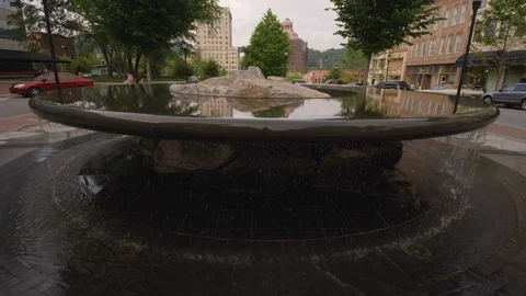 Medium shot of water overflowing from a flat fountain amidst the city street Stock Footage 103431040