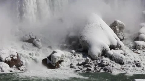 Medium shot of waterfall pouring down on to snow covered rocks Stock Footage 208678260