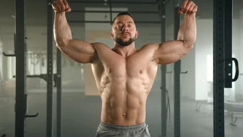 Medium shot of weightlifter flexing arms with fists, showing biceps, triceps Stock Footage 240587812