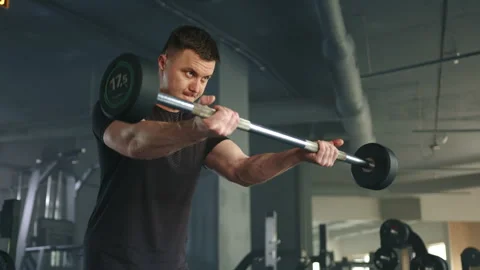 Medium shot of young athlete performing exercises with barbell in gym Stock Footage 241585284