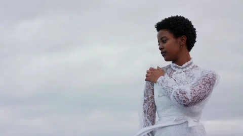 Medium shot of Young Beautiful Black woman in white dress at the beach Stock Footage 220568602