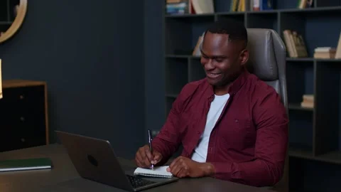 Medium shot of a young black man in profile in a shirt talking online with a Vidéo 262851264