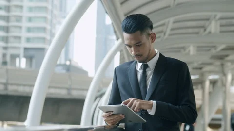 Medium shot. Young businessman using a tablet while standing Walkways Stock Footage 120812560