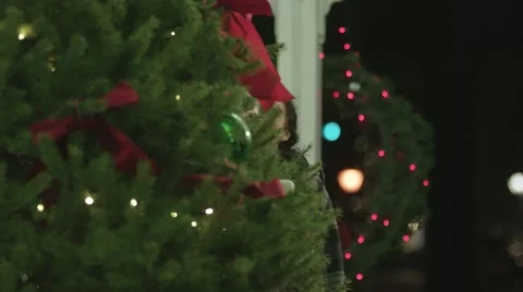 Medium shot of young couple in gazebo finding a gift hidden in the Xmas tree Stock Footage 59458174