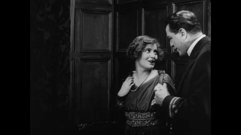 Medium shot of young couple hearing good news and kissing behind door. UK 1917 Stock Footage 131079916