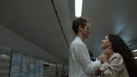Medium shot of a young couple hugging and smiling on a platform in the subway. Stock Footage 116023939