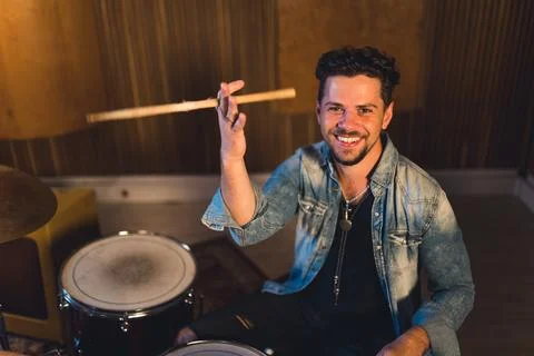 Medium shot of a young drumer man holding drums sticks and smiling widely Stock Photos