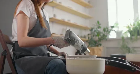 Medium shot of young female potter in pottery workshop. Woman in apron is drying Stock Footage 155358317