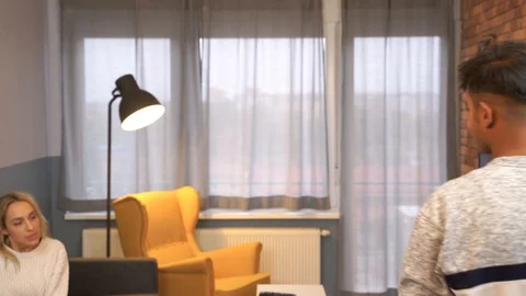 Medium shot of a young interracial couple having a pillow fight at living room. Stock Footage 119301715