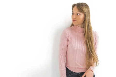 Medium shot of a young long-haired girl posing against the white wall and Stock Photos
