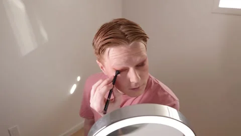 A Medium Shot of A Young Man Applying Eyeshadow in Front of Mirror Stock Footage 310031583