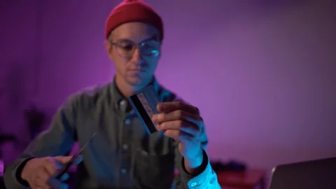 Medium shot young man cuts up his credit card. Neon light Stock Footage 127582125