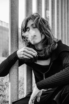 Medium shot of young man holding a cigar while blowing smoke from his mouth Stock Photos