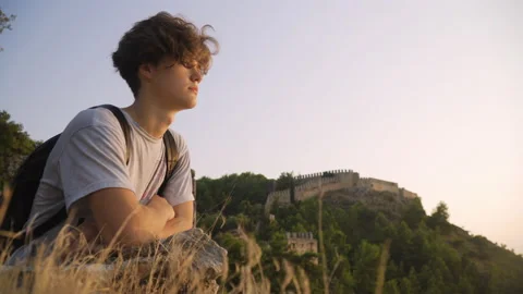 Medium shot of a young man looking at a view at sunset Stock Footage 142550431