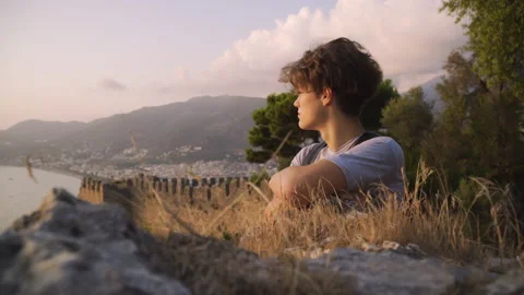 Medium shot of a young man looking at a view at sunset Stock Footage 142550453