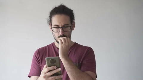Medium shot of young man looking at smartphone and biting his nails Stock Footage 161551835