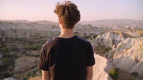 Medium shot of young man on mountain top overlooking view and sunset Stock Footage 142550288